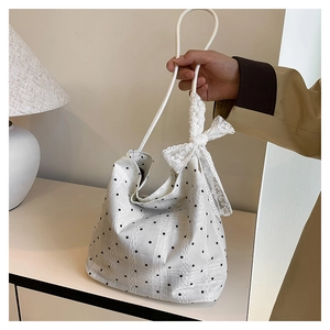 Détail du sac seau blanc à pois noirs avec un grand nœud en dentelle élégant
