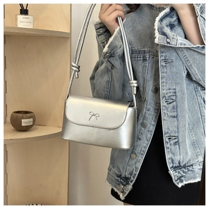 Detail of silver metallic crossbody bag with bow accent and minimalist knotted strap