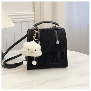 Detail of black multi-functional bag with silver buckles and a white cloud charm
