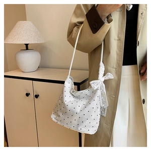 Détail du sac seau blanc à pois avec nœud en dentelle et texture tissée élégante