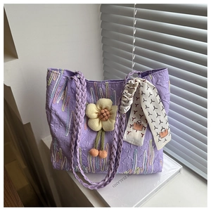 Detail of purple jacquard tote bag with woven handles and 3D sunflower charm detail