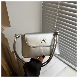 Detail of silver crossbody bag with metal bow accent and sleek rectangular PU structure