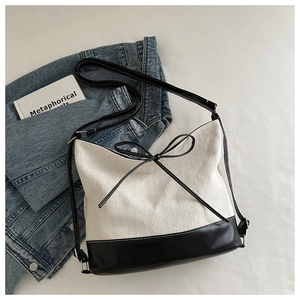 Nahaufnahme der minimalistischen Canvas-Tasche mit schwarzem Lederbesatz und Schleifendetail