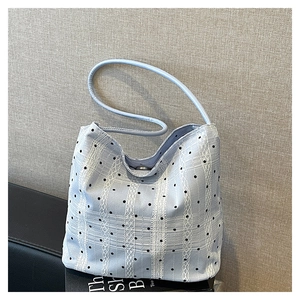 Détail du sac seau bleu clair avec des rayures en dentelle blanche et des pois noirs
