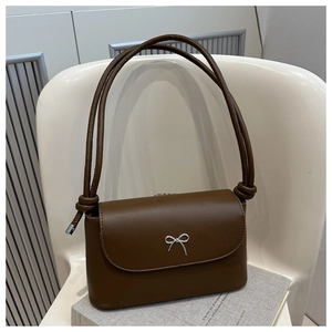 Detail of dark brown shoulder bag with silver bow buckle and knot-tie strap detail