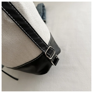 Nahaufnahme der Canvas-Tasche mit Fischgrätmuster, Lederbesatz und Schnalle aus Silber