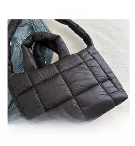 Detail of black quilted down tote bag featuring padded square texture and soft handle
