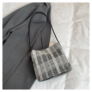 Détail du sac seau avec texture quadrillée grise et fines lanières en cuir noir