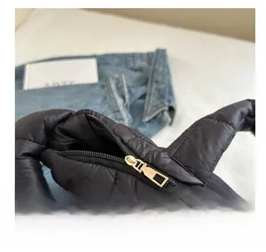 Close-up of the smooth gold zipper and black quilted fabric on the padded puffer bag