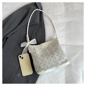 Détail du sac seau blanc à pois noirs avec un nœud décoratif en dentelle élégante