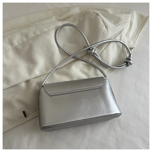 Detailed view of silver leather shoulder bag with a unique knot decorative strap design