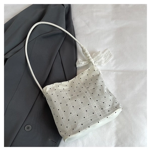 Détail du sac bandoulière en dentelle blanche avec pois noirs et un grand nœud