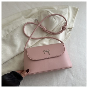 Close-up of pink shoulder bag with a silver metal bow buckle and smooth leather texture