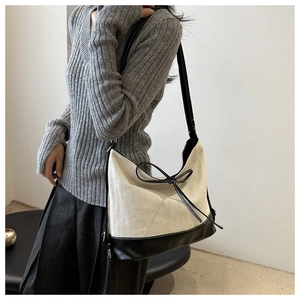 Detail der Canvas-Tasche mit schwarzem Lederbesatz und eleganter Schleife am Modell