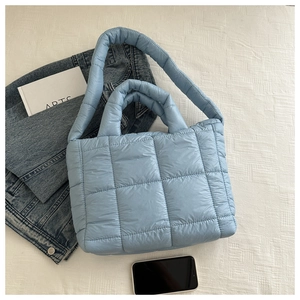 Detailed top view of light blue quilted tote bag with dual handles on neutral background