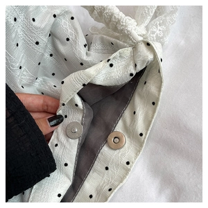Détail du sac seau blanc à pois avec fermeture magnétique et bandoulière en dentelle