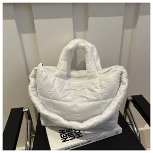 Macro shot of white quilted down tote bag with glossy finish on urban housing book
