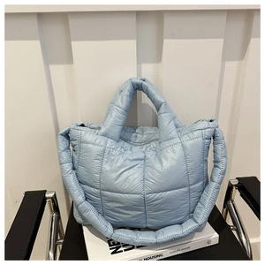 Detail view of light blue quilted tote bag showing padded texture and dual handle straps