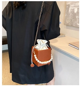 Detail of orange wave pattern crossbody bag with pearl handle and white drawstring liner