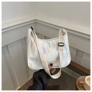 Detail of white nylon bag featuring colorful vertical embroidery and brand leather patch