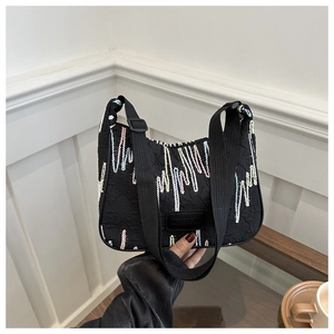 Detail of black nylon crossbody bag featuring colorful wavy embroidery and brand label