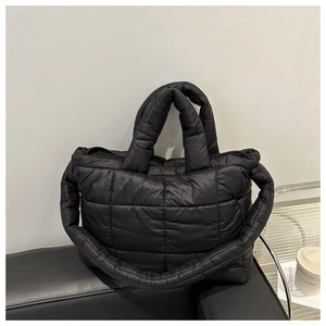 Detail of modern black quilted puffer tote showing padded texture and thick shoulder strap