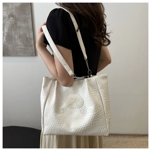 Macro view of woven texture and brand patch on a beige oversized tote shoulder bag