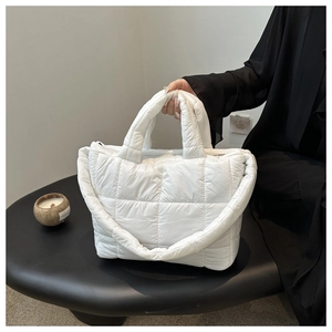 Detail of white quilted tote bag featuring a padded square texture and wide strap