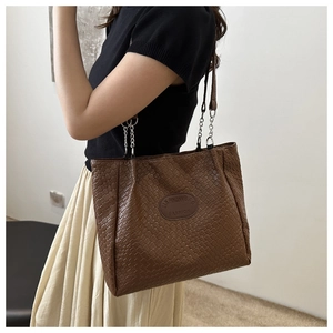 Detail of dark brown woven tote bag featuring chain strap and textured leather finish
