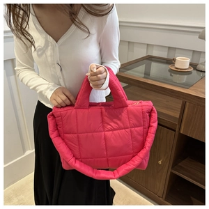 Hot pink quilted down tote bag worn by model in a warm minimalist indoor setting