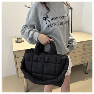 Close-up of black quilted nylon tote bag with thick padded handles for winter style