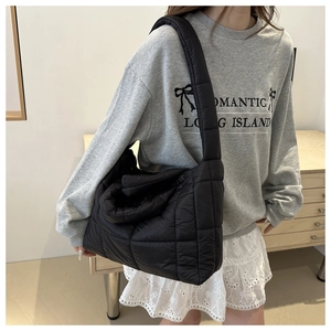 Detailed side view of black quilted down tote bag worn as a shoulder bag