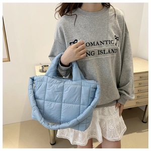 Detail of light blue quilted tote bag with soft puffer material and padded top handle