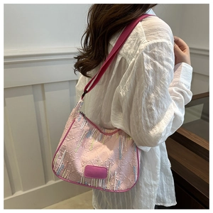 Detail of pink nylon crossbody bag featuring colorful embroidery and logo patch