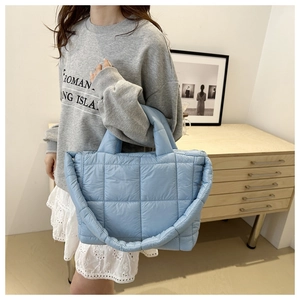 Close-up of light blue quilted puffer tote bag with soft padded texture and wide shoulder strap