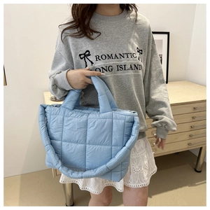 Detail of light blue quilted tote bag showing soft padded texture and dual straps