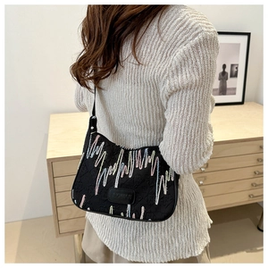 Detail of black textured tote bag with colorful gradient stripe embroidery and leather patch