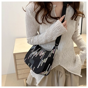 Detailed shot of a black tote with colorful wave embroidery and adjustable wide strap