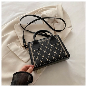 Detail of black quilted square handbag with gold heart embroidery and chain strap
