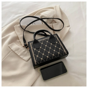 Detail of black small square bag with beige heart embroidery and detachable strap