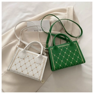 Detail of white and green quilted handbags with gold heart embroidery on a beige blazer