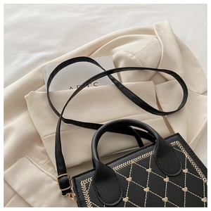 Close-up of quilted square bag with heart embroidery on a beige blazer jacket