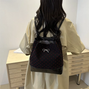 Women's black bucket backpack with red heart print and silver bow buckle on model