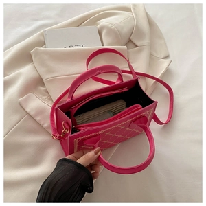 Macro detail of magenta quilted crossbody bag with golden hardware and interior zip pocket