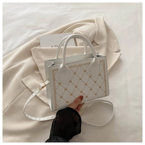 Detail of white quilted crossbody bag with heart embroidery and golden stitching