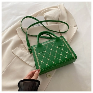 Detail of green square bag featuring quilted diamond pattern and white heart embroidery