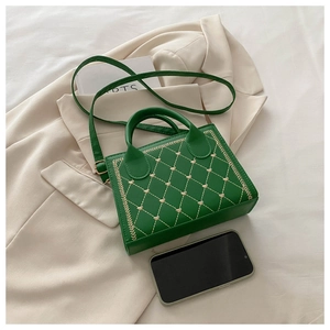 Detail of green shoulder bag with heart embroidery and phone for size comparison