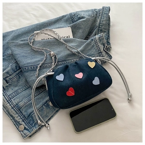 Detail of dark blue denim bucket bag with colorful heart patches and chain strap