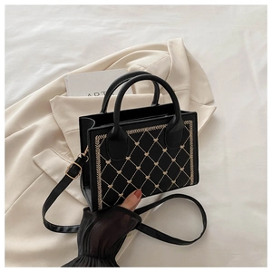 Detail of black vintage square bag with gold heart embroidery on beige blazer