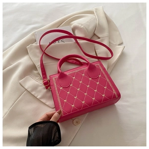Close-up of hot pink quilted handbag with gold heart embroidery and top handle details